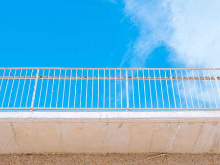 Railing against a blue sky photographed from belowの写真素材