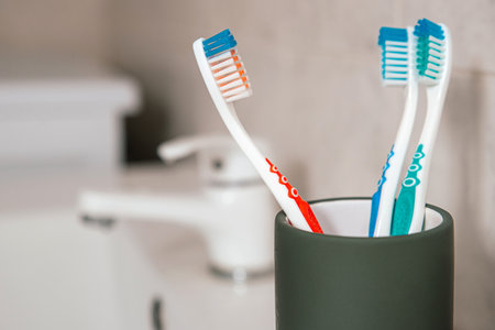 Three different colorful toothbrushes in a grey glass in a bathroomの写真素材