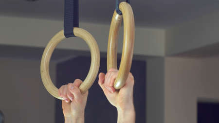 Man Works Out Pull-ups on Gymnastics Rings at Homeの写真素材