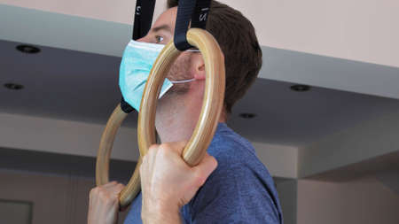 Man in Surgical Mask Works Out on Gymnastics Rings at Virus Epidemic Quarantine
