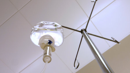 Patient on a Drip Looking up at Drip-Bag from Hospital Bedの写真素材
