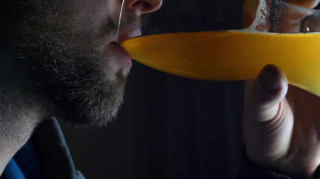 Bearded Caucasian Man Drinking Beer from Pint Glass on Dark Backgroundの写真素材