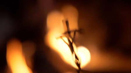 Blurred Crucifix Silhouette on Fire Flames Dark Background Slow Motionの写真素材
