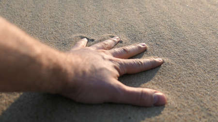 Adult Male Hand Leaves Handprint on Sandy Beach at Sunsetの写真素材