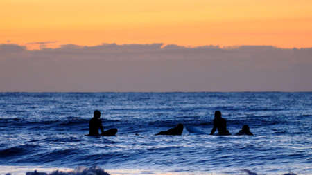 Silhouettes of Surfers Waiting for Waves on Baltic Sea after Sunset Slow Motionの写真素材
