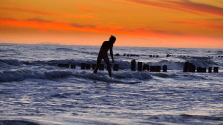 Silhouette of Surfers Surfing Waves on Baltic Sea after Sunset Slow Motion