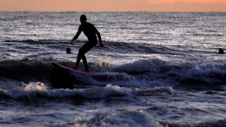 Silhouette of Surfers Surfing Waves on Baltic Sea after Sunset Slow Motion