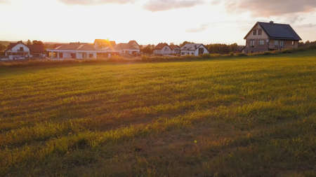 Aerial of Residential Village Houses Surrounded by Meadows at Sunsetの写真素材