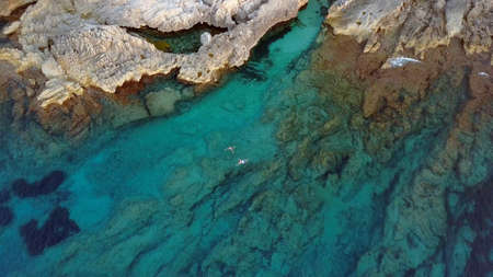 Aerial of People Swimming in Turquoise Sea at Rocky Coastline