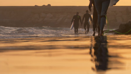 Silhouettes of Surfers Walking on Atlantic Ocean Coast at Sunset in Moroccoの写真素材