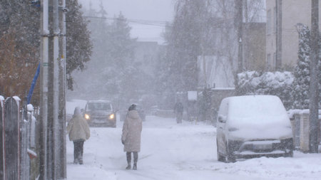 Anonymous People on Neighbourhood Street in Heavy Winter Snowstorm Slow Motionの写真素材