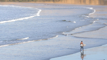 Anonymous Surfer walking on Atlantic Ocean Coast Sandy Beach in Morocco