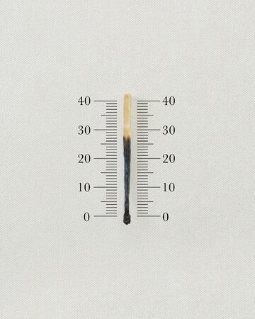 Thermometer made by a burnt match on white background.の写真素材