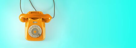 Orange vintage dial telephone with blue background.の写真素材