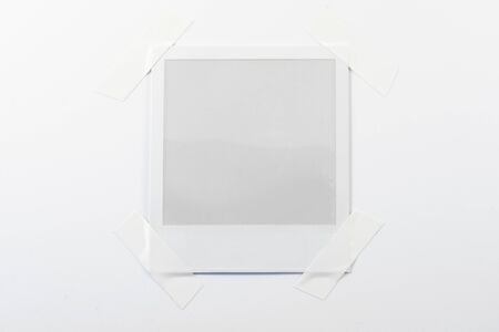 An empty polaroid picture stuck on a sheet of paper.の写真素材