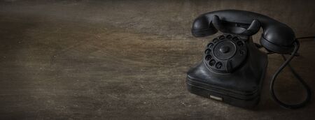 A black vintage dial telephone with woody background.の写真素材