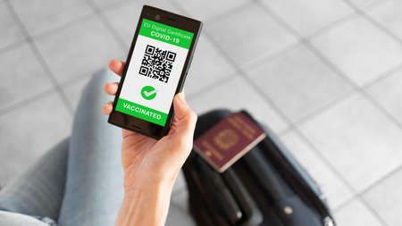 EU Digital Certificate app for smartphone with vaccinated sign and quad code. Woman leaving with passport and baggage. Covid-19 concept.の写真素材