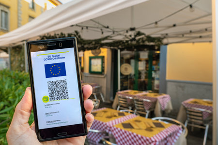 Woman showing on smartphone EU Digital Covid Certificate Green Pass with quad code. Restaurant background.の写真素材