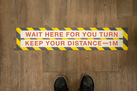 Wait your turn, keep your distance sign on a store floor. Coronavirus pandemic social distance.の写真素材