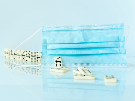 Surgical mask stopping domino effect falling. Covid-19 concept.の写真素材