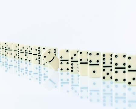 Domino piece stopping domino effect falling. Concept with a solution and intervention.の写真素材