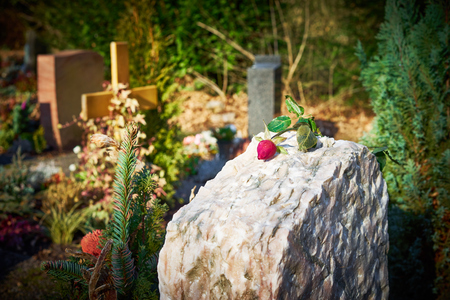 Gravestone with withered rose Tomb stone on graveyard Sorrow about loss of beloved onesの写真素材