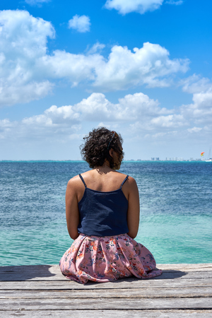 Lonesome woman sitting on pierの写真素材