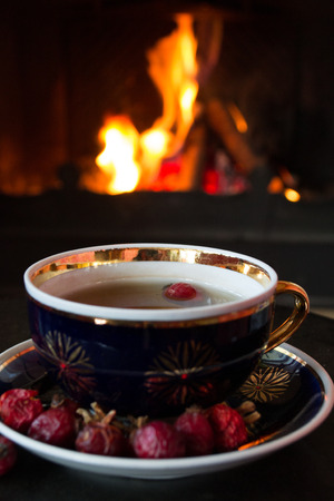 Rosehip tea in front of roaring fire in a fire placeの写真素材