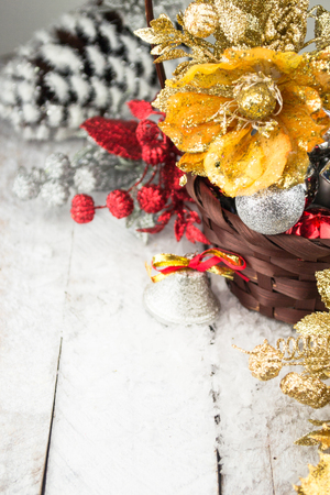Brown Christmas basket with silver and gold toys on a white wooden backgroundの写真素材