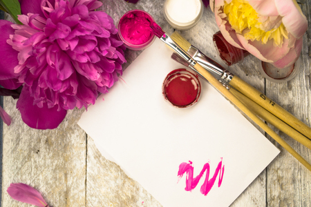 Workspace. Watercolor, paintbrush and pink peonies isolated on white background. Overhead view. Flat lay, top viewの写真素材