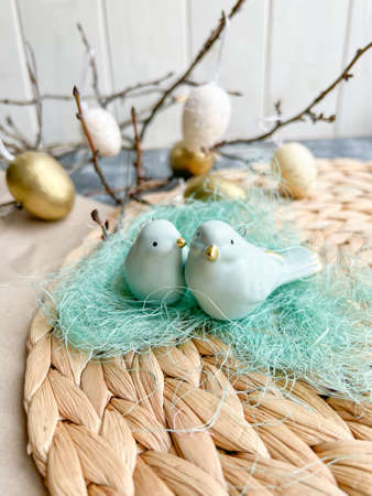 Easter composition with birds, eggs and branches on a wooden background.