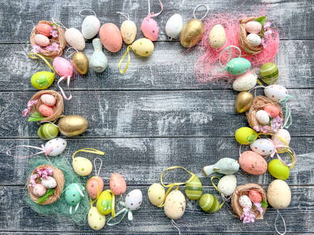 Easter frame with colored eggs and feathers on rustic wooden backgroundの写真素材