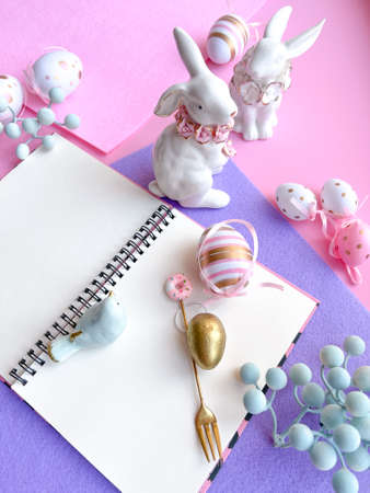 Easter table setting with notepad, bunny and eggs on pink backgroundの写真素材