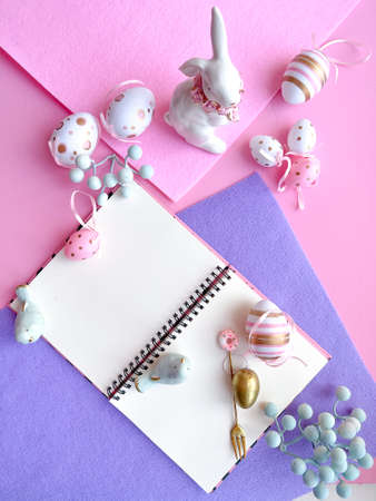Easter greeting card with blank notepad, bunny and eggs on pink and purple background