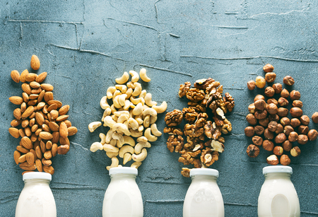 four kinds of vegetable milk in glass jars on a dark concrete backgroundの写真素材