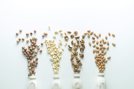vegan milk in glass jar with ingredients on white background with copy spaceの写真素材