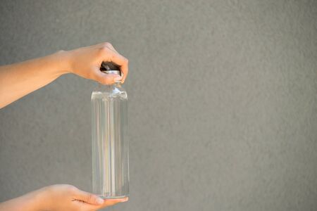 woman is holding and drinking from glass reusable bottle with clear waterの写真素材