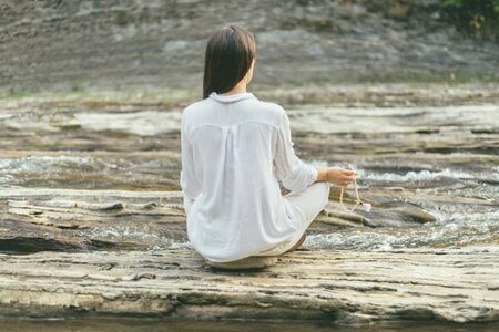 peaceful woman is making mantra meditation near river holding beans in her handの写真素材