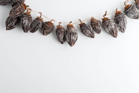 dried persimmon hanging on rope on white backgroundの写真素材