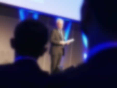 Speech at business convention blur effect close up view on spokesman and silhouette listenersの写真素材