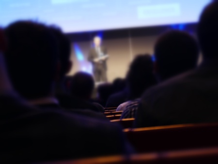 Speech at business convention blur effect close up view on spokesman and silhouette listenersの写真素材