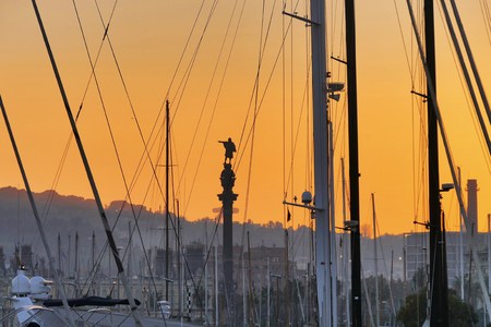 Cristoforo Colombo statue silhouette view through trees and shrouds of the boats moored in the port at sunset Barcelona Catalunya Spain circa November 2016の写真素材