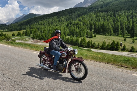 Italy Piedmont Alps circa June 2015 Single vintage motorbike rider front view on mountain landscape with cloudy skyのeditorial素材
