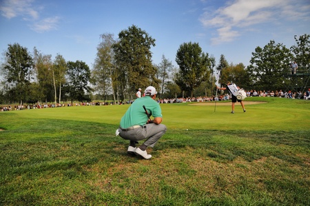 Turin Italy about September 2016 Unknown golf player concentrate seek the right line squatted on the green with wide crowd in the backgroundのeditorial素材