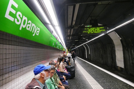 Barcelona Spain circa November 2016 Barcelona metro station tunnel with people seated waiting for train sign in foregroundのeditorial素材