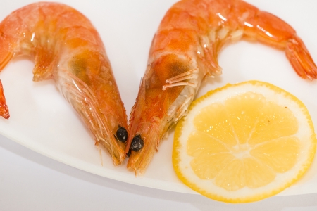 two shrimp with lemon on a plateの写真素材