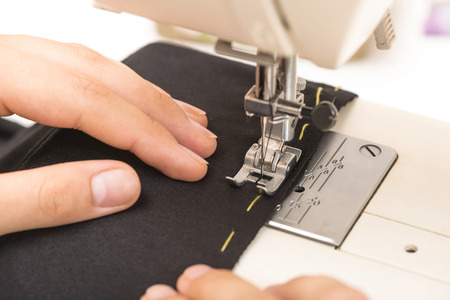 woman sews clothes on a sewing machine