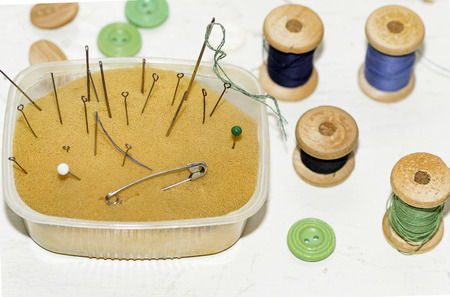 old rusty metal needles, pins and wooden spools of thread
