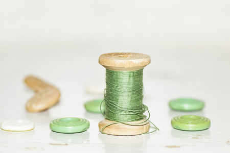 wooden bobbin with green threads and buttonsの写真素材
