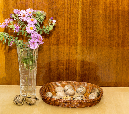 flowers in a vase and walnuts on a wooden tableの写真素材
